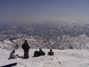 浅草岳山頂で憩う登山者。銀山湖を見下ろす。遥かに平ヶ岳方面の尾瀬が見える。